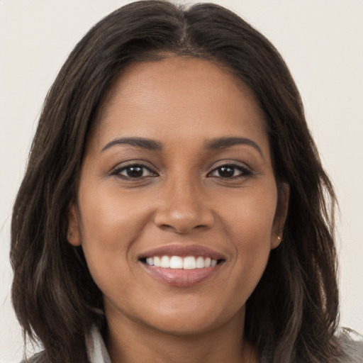 Joyful black young-adult female with long  brown hair and brown eyes