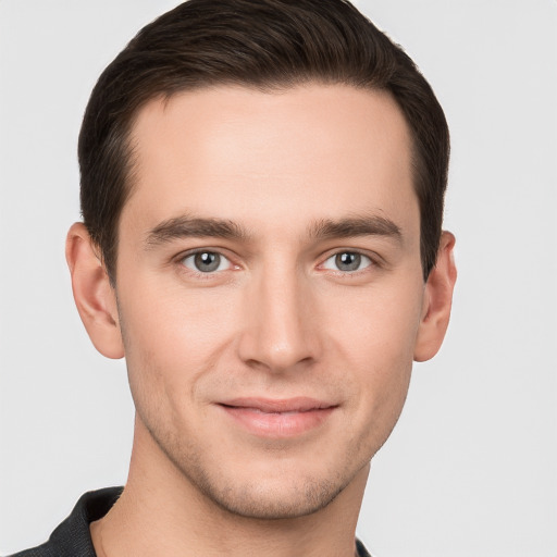 Joyful white young-adult male with short  brown hair and grey eyes