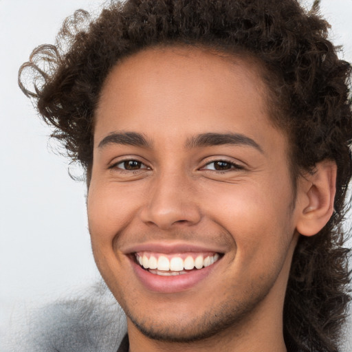 Joyful white young-adult male with long  brown hair and brown eyes