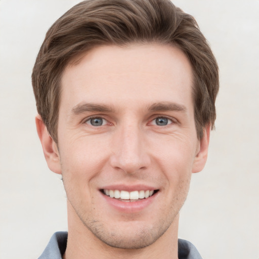 Joyful white young-adult male with short  brown hair and grey eyes