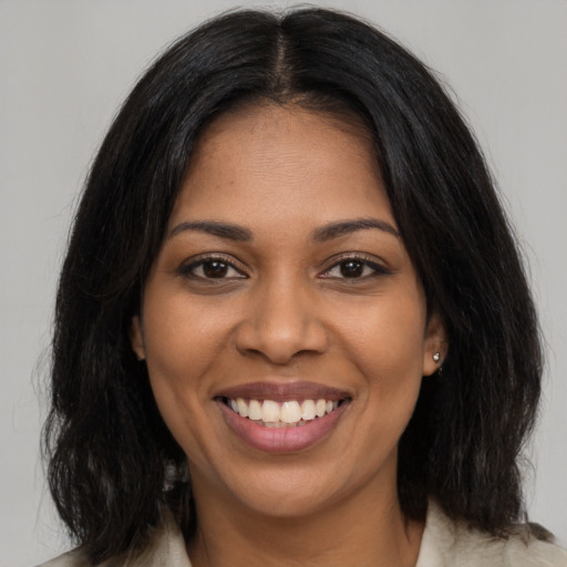 Joyful black young-adult female with long  brown hair and brown eyes