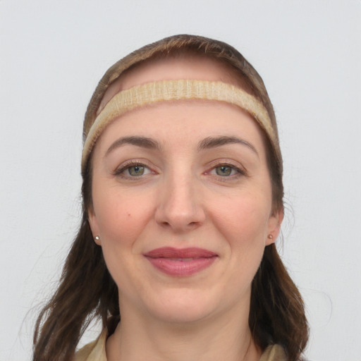 Joyful white young-adult female with long  brown hair and grey eyes