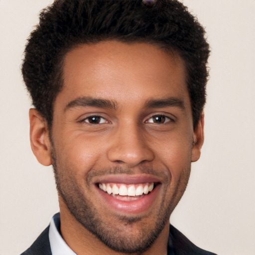 Joyful black young-adult male with short  brown hair and brown eyes