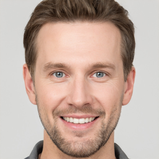 Joyful white young-adult male with short  brown hair and grey eyes