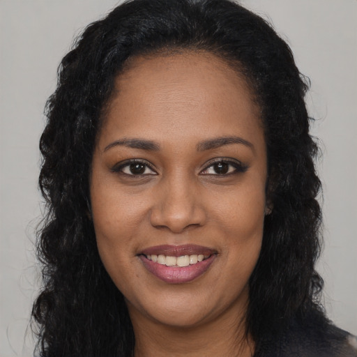 Joyful black young-adult female with long  black hair and brown eyes