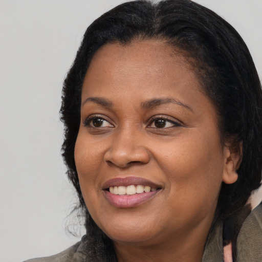 Joyful black adult female with long  brown hair and brown eyes