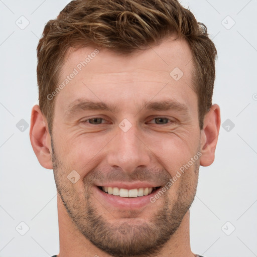 Joyful white young-adult male with short  brown hair and grey eyes