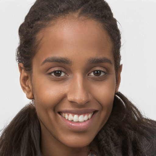 Joyful black young-adult female with long  brown hair and brown eyes