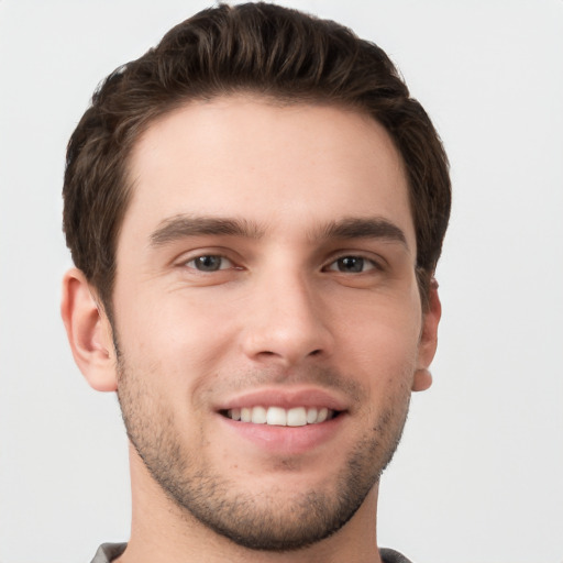 Joyful white young-adult male with short  brown hair and grey eyes