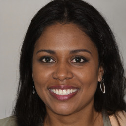 Joyful black young-adult female with long  brown hair and brown eyes