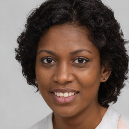 Joyful black young-adult female with long  brown hair and brown eyes