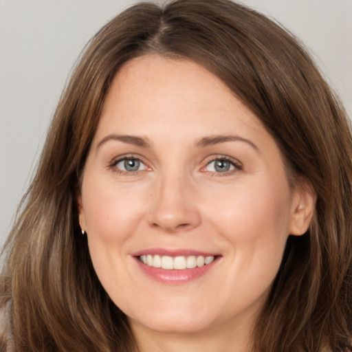 Joyful white young-adult female with long  brown hair and grey eyes