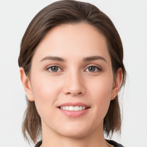 Joyful white young-adult female with medium  brown hair and grey eyes