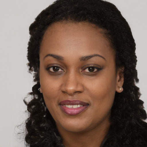 Joyful black young-adult female with long  brown hair and brown eyes