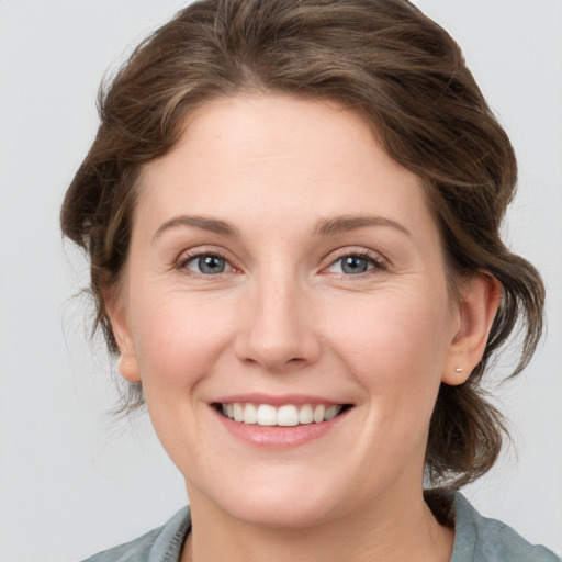 Joyful white young-adult female with medium  brown hair and grey eyes