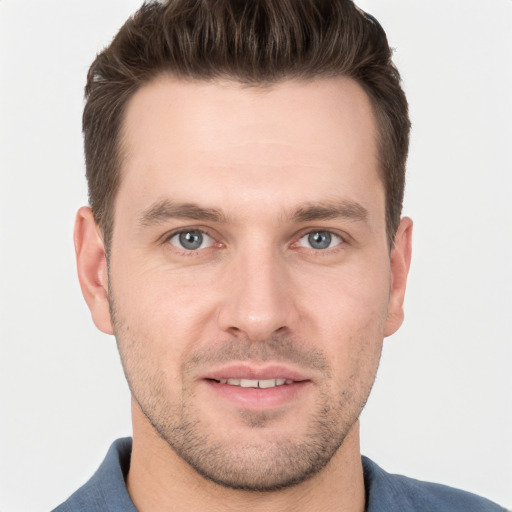 Joyful white young-adult male with short  brown hair and grey eyes