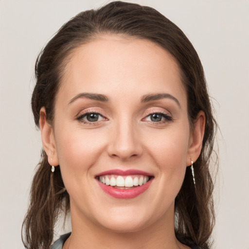 Joyful white young-adult female with medium  brown hair and grey eyes