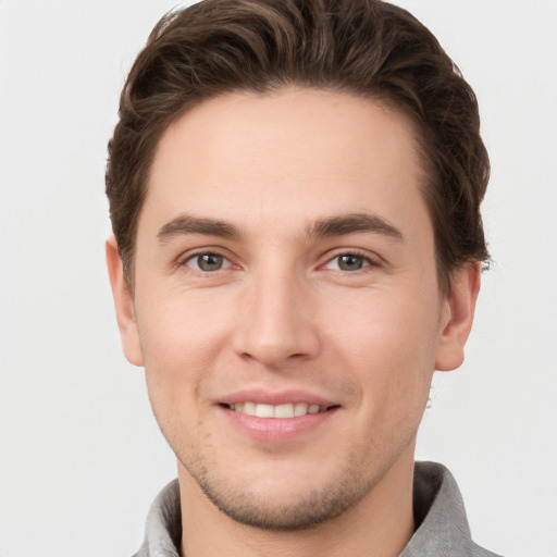 Joyful white young-adult male with short  brown hair and grey eyes