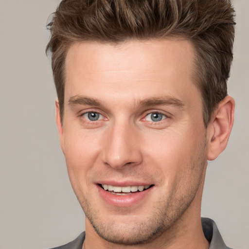 Joyful white young-adult male with short  brown hair and grey eyes