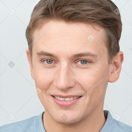 Joyful white young-adult male with short  brown hair and grey eyes