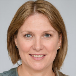 Joyful white adult female with medium  brown hair and blue eyes