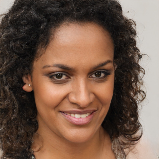 Joyful black young-adult female with long  brown hair and brown eyes