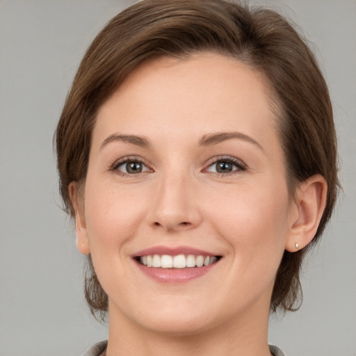 Joyful white young-adult female with medium  brown hair and grey eyes