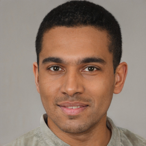 Joyful black young-adult male with short  brown hair and brown eyes