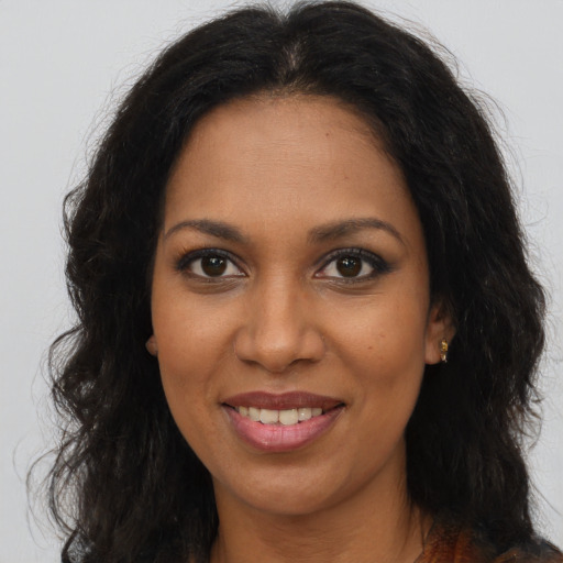 Joyful black young-adult female with long  brown hair and brown eyes