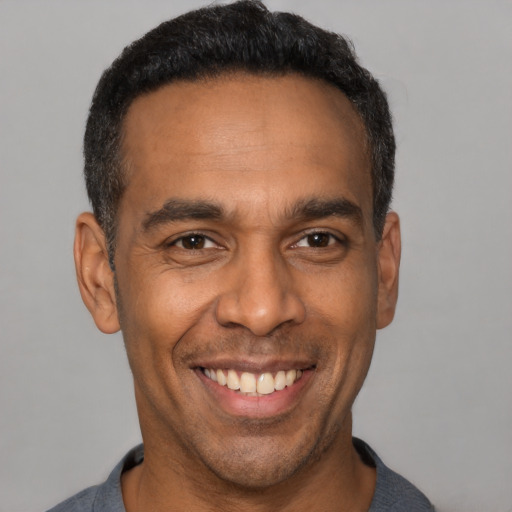 Joyful black adult male with short  black hair and brown eyes