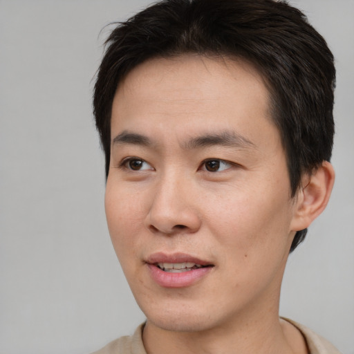 Joyful asian young-adult male with short  brown hair and brown eyes