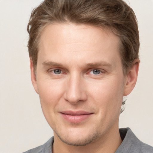 Joyful white young-adult male with short  brown hair and grey eyes