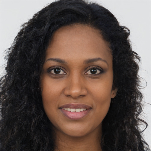 Joyful black young-adult female with long  brown hair and brown eyes