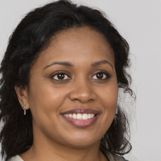 Joyful black young-adult female with long  brown hair and brown eyes