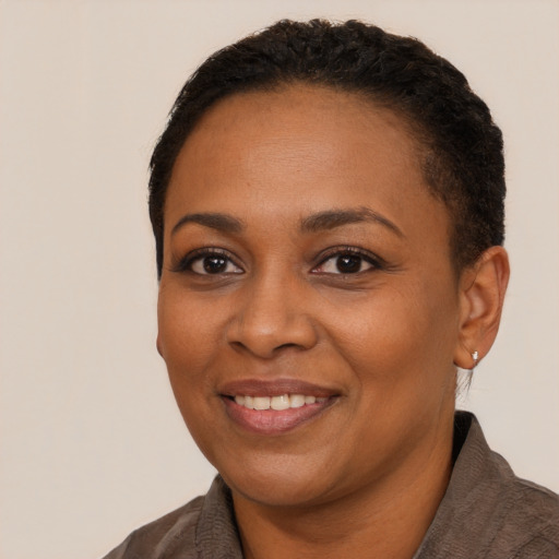 Joyful black adult female with short  black hair and brown eyes