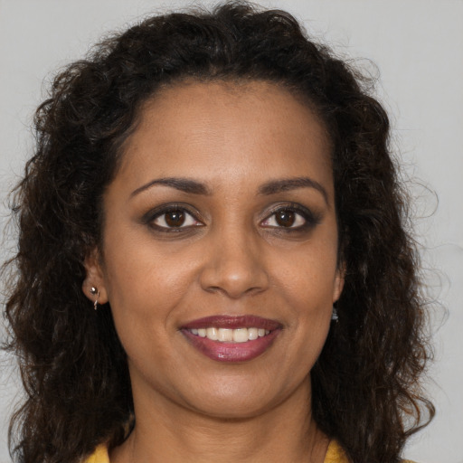 Joyful black adult female with long  brown hair and brown eyes