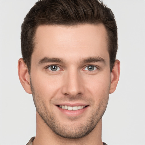 Joyful white young-adult male with short  brown hair and grey eyes