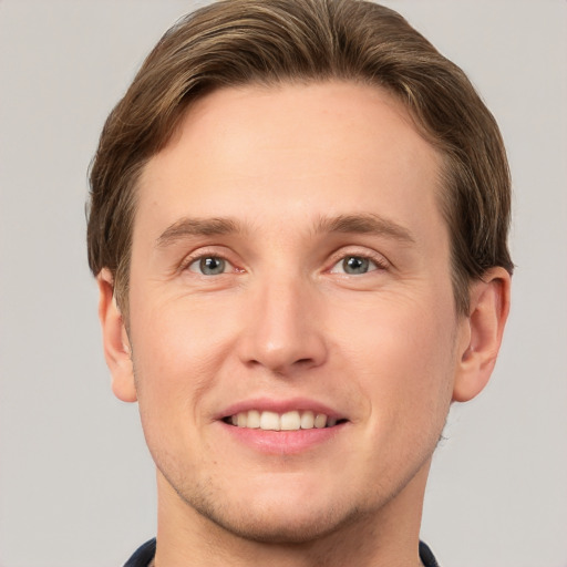 Joyful white young-adult male with short  brown hair and grey eyes