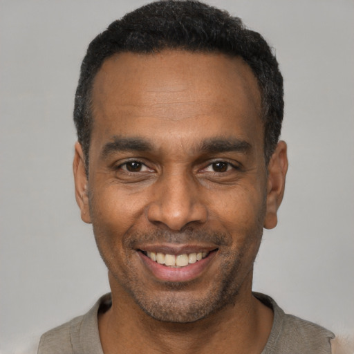 Joyful black young-adult male with short  black hair and brown eyes