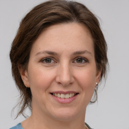 Joyful white young-adult female with medium  brown hair and grey eyes