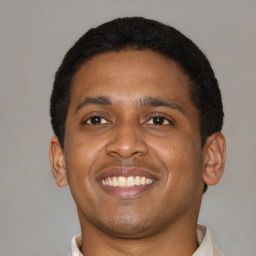 Joyful latino young-adult male with short  brown hair and brown eyes