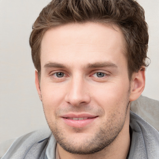 Joyful white young-adult male with short  brown hair and grey eyes