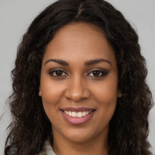 Joyful black young-adult female with long  brown hair and brown eyes