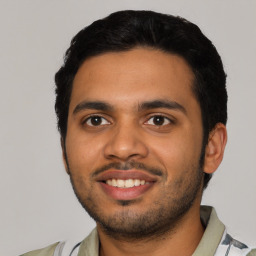 Joyful latino young-adult male with short  black hair and brown eyes