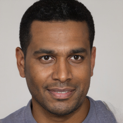 Joyful black young-adult male with short  brown hair and brown eyes