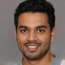 Joyful latino young-adult male with short  black hair and brown eyes