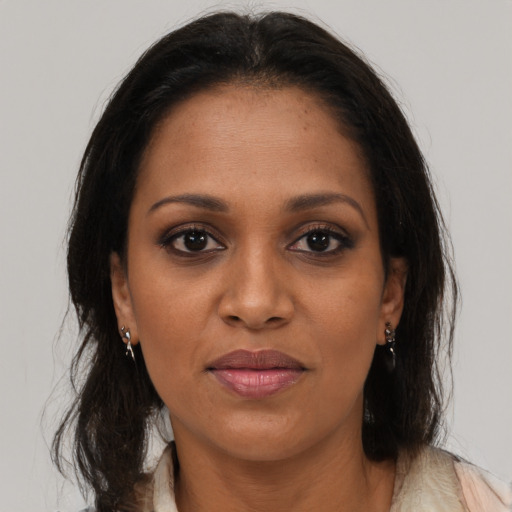 Joyful black young-adult female with long  brown hair and brown eyes