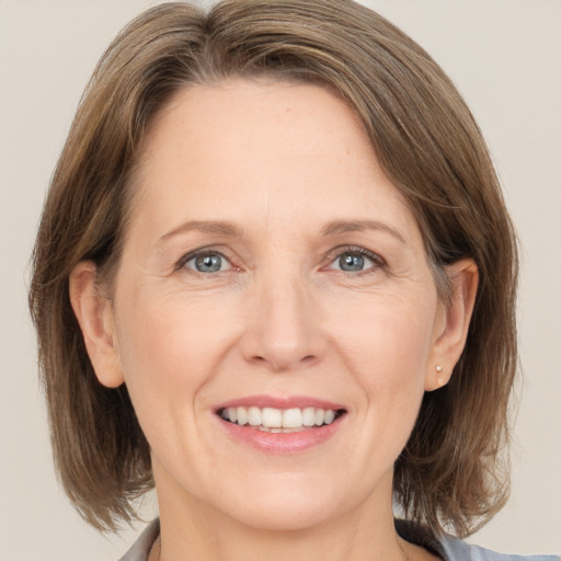 Joyful white adult female with medium  brown hair and grey eyes