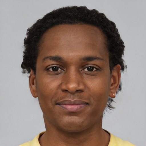Joyful black young-adult male with short  brown hair and brown eyes