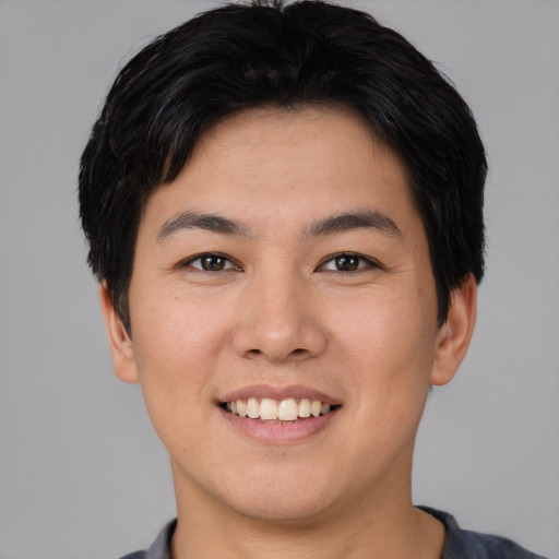 Joyful asian young-adult male with short  brown hair and brown eyes